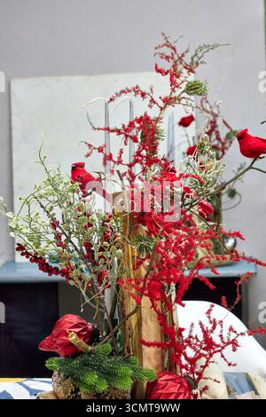 Festività natalizie con cardinali rossi, candele, rami di pino, bacche e ornamenti. Vacanza rustica che crea un ambiente caldo e commerciale Foto Stock