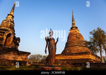Statua di Buddha a piedi e stupa nell'antica Wat sa si, Parco storico di Sukhothai, Thailandia. Foto Stock