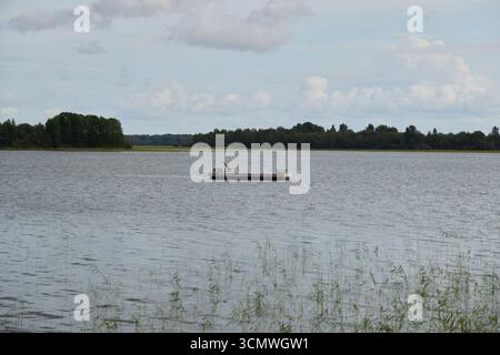 Una splendida e tranquilla scena di un lago tranquillo con una barca sotto uno splendido cielo nuvoloso Foto Stock