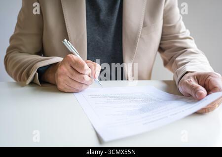 Uomo d'affari che deve completare un sondaggio o un documento di valutazione. Vista ravvicinata. Foto Stock