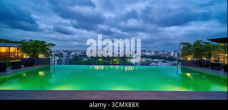 Splendida piscina a sfioro sul tetto con vista panoramica sulla città, perfetta per un soggiorno di lusso e relax. Foto Stock