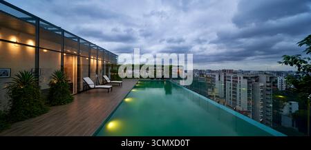 Splendida piscina a sfioro sul tetto con vista mozzafiato sulla città, che offre un esclusivo rifugio di lusso per il relax e lo svago. Foto Stock