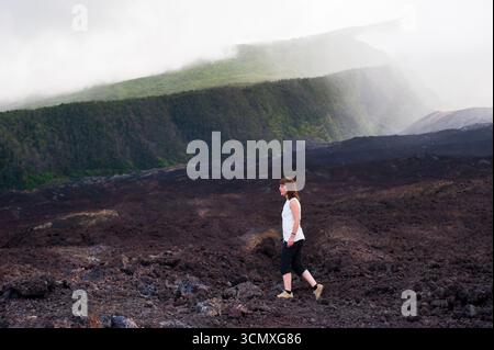 Donna che cammina sul flusso di lava fredda, le Grand Brule Coast, Reunion Foto Stock