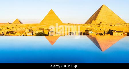 Panoramica del complesso piramidale di Giza e della Sfinge riflessa nell'acqua all'alba, il Cairo, l'Egitto Foto Stock
