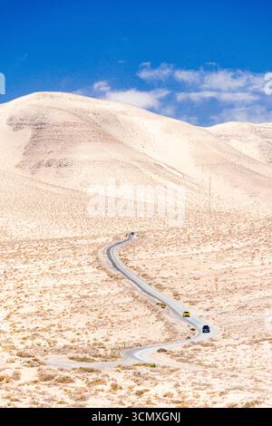 Vista ad alto angolo delle auto che guidano su una tortuosa strada desertica nel paesaggio arido, Jandia, Fuerteventura, Isole Canarie, Spagna Foto Stock