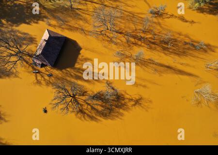Vista aerea della casa del villaggio che affonda nel mezzo del laghetto di decantazione della miniera di acidi tossici. Geamana, Rosia Montana, Romania Foto Stock