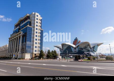 Baku, Azerbaigian - 25 marzo 2025: Un paesaggio urbano caratterizzato da un'architettura moderna con un edificio classico e una caratteristica struttura alberata sul tetto. Dalga P. Foto Stock