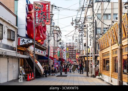 Osaka, Giappone - dicembre 2023: Strada trafficata con cartelli colorati per ristoranti e gente che cammina nel quartiere shinsekai Foto Stock