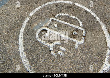 Simbolo di ricarica per auto elettriche dipinto sulla strada. Questa immagine ravvicinata mostra la segnaletica sull'asfalto per i veicoli di nuova tecnologia. Foto Stock