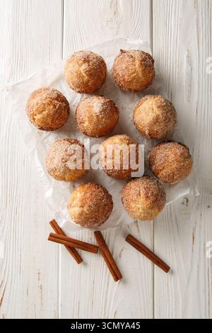 Muffin alla francese appena sfornati arrotolati nel burro fuso e ricoperti da zucchero alla cannella da vicino sul tavolo di legno. Vista dall'alto verticale Foto Stock