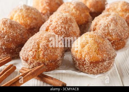 Muffin alla francese appena sfornati arrotolati nel burro fuso e ricoperti da zucchero alla cannella da vicino sul tavolo di legno. Orizzontale Foto Stock
