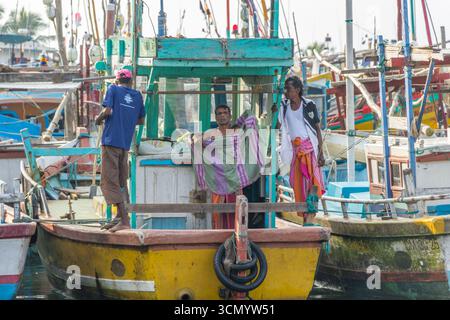 Sri Lanka - Mirissa - Porto di pesca - pescatori locali in piedi su una vivace barca Foto Stock