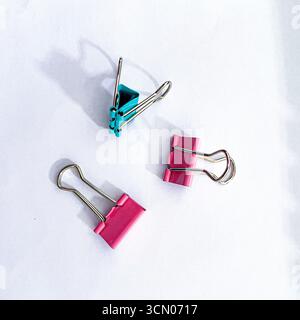 disposizione di piccole graffette per carta legante in vari colori su sfondo bianco Foto Stock