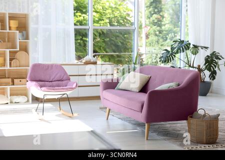 Soggiorno con divano rosa e sedia a dondolo. Design degli interni Foto Stock