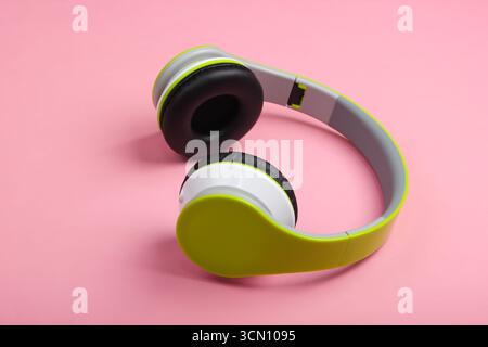 Eleganti cuffie stereo wireless con sfondo rosa pastello. Amante della musica. Gadget. Foto Stock
