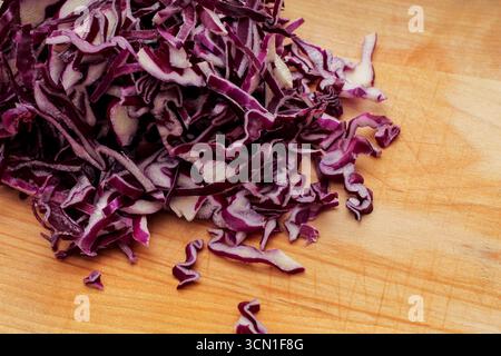 Primo piano del cavolo rosso tritato su tagliere di legno Foto Stock