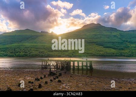 Regno Unito - Arrochar - Loch Long - il tramonto si illumina sulle verdi colline e su un molo con maree intemperie Foto Stock