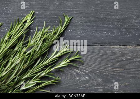 Ramoscelli di rosmarino freschi su sfondo di legno nero Foto Stock