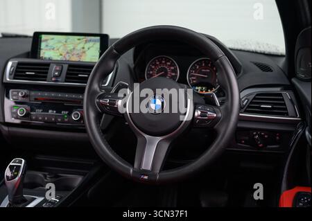 Derby, Regno Unito - 19 settembre 2025: Volante BMW, con l'iconico logo BMW Roundel, pulsanti multifunzione integrati Foto Stock