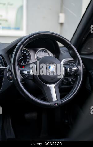 Derby, Regno Unito - 19 settembre 2025: Volante BMW, con l'iconico logo BMW Roundel, pulsanti multifunzione integrati Foto Stock