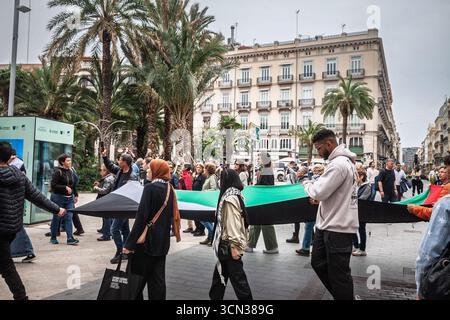 VALENCIA, SPAGNA - 12 APRILE 2025: Le persone marciano attraverso il centro di Valencia portando una grande bandiera palestinese durante una manifestazione a sostegno di Gaza, duri Foto Stock