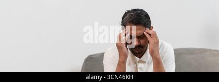 Primo piano di uomo di mezza età che tiene la testa con le mani che toccano templi, soffre di grave mal di testa, stress o emicrania, concetto di problema di salute, m Foto Stock