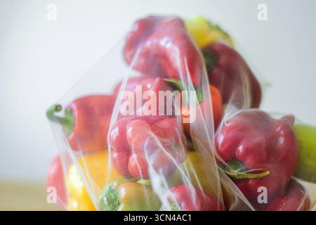 Verdure in confezioni ecologiche: Peperoni multicolori in una borsa riutilizzabile in rete. Cultura della spesa consapevole, consumismo etico, dieta cruda Foto Stock