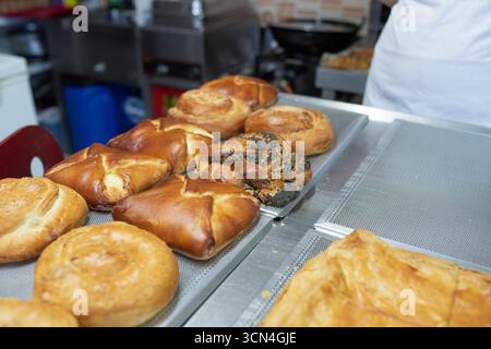Prodotti appena sfornati esposti su un vassoio presso una panetteria locale. Foto Stock