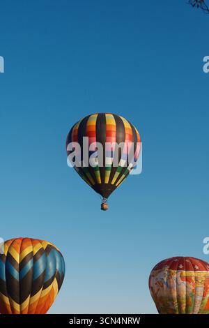 I coloratissimi palloncini ad aria calda fluttuano con grazia contro un cielo azzurro. Foto Stock
