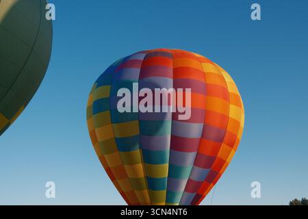 Coloratissima mongolfiera contro un cielo blu chiaro Foto Stock