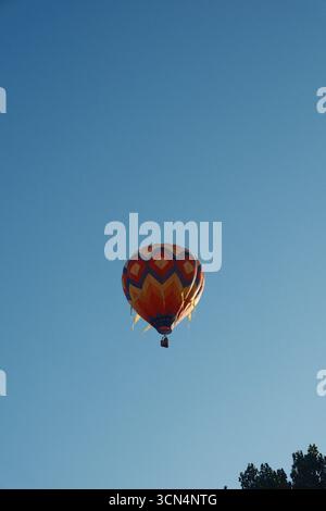 Pallone colorato ad aria calda che si innalza nel cielo azzurro. Foto Stock