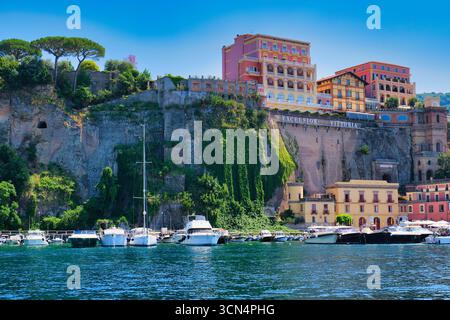 Vista dal basso delle scogliere con edifici e yacht a Sorrento, Italia Foto Stock