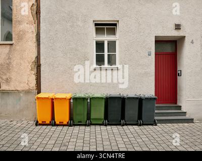 Bidoni colorati in piedi davanti all'edificio Foto Stock