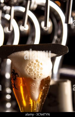 Cattura il momento rinfrescante di una birra dorata, creando una schiuma perfetta. Perfetto per esibire birrerie, pub o cene informali. Foto Stock