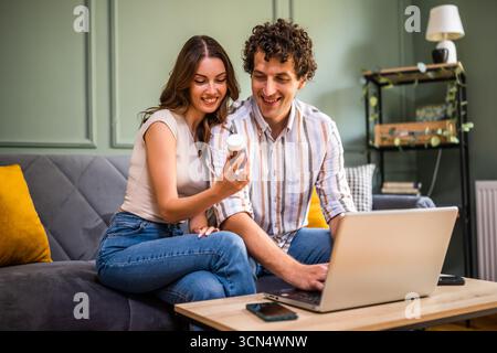 Coppia adulta seduta sul letto nel soggiorno e appuntamento medico online con il computer portatile. Donna che soffre di stomaco. Consulenza remota con d Foto Stock