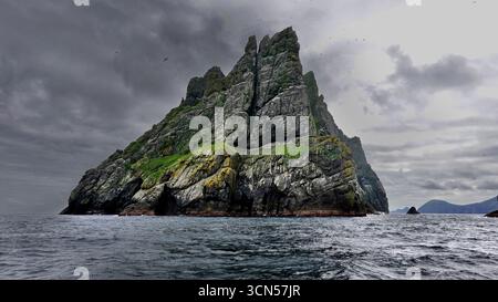 Gannetti che ruotano intorno alla maestosa isola di Boreray, l'arcipelago di St Kilda Foto Stock