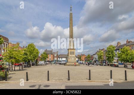 L'obelisco di Ripon nella piazza del mercato, North Yorkshire, un monumento classificato Grade i costruito nel 1702, visto su uno spazio pubblico lastricato con negozi Foto Stock
