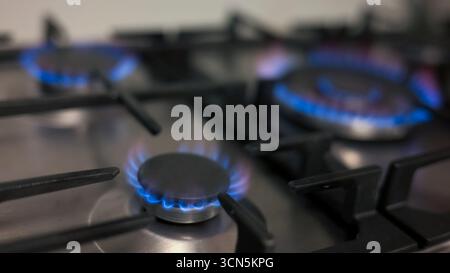 Fornelli illuminati in una cucina a gas, bruciati con fiamme blu, pronti per la cottura, colpo ravvicinato. Concetti di finanza, economia e famiglia. Foto Stock