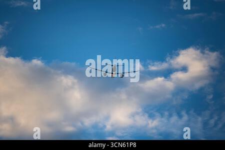 Pancia o parte inferiore di un aereo passeggeri commerciale visto da terra, vista posteriore. Teleobiettivo da vicino, cielo blu con sfondo nuvoloso, nessuna persona Foto Stock
