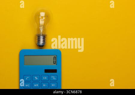 Ho un'idea! Calcolatrice e lampadina su sfondo giallo. Concetto di risparmio energetico Foto Stock