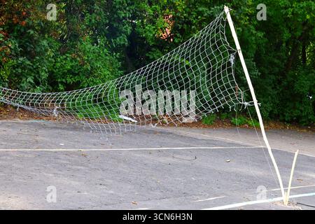 Rete da pallavolo fatiscente su un campo di cemento Foto Stock