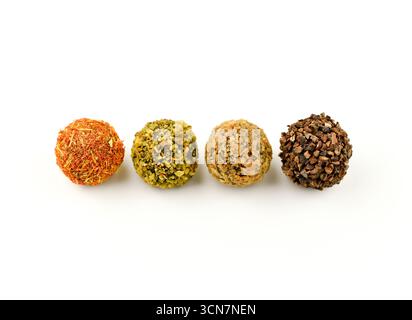 Quattro palline colorate con nocciole e spezie. Le palle sono disposte in fila su uno sfondo bianco Foto Stock