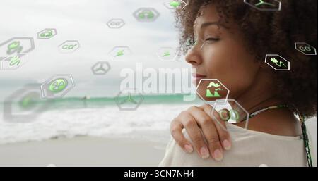 Donna in piedi in alto davanti a destra sulla spiaggia, con icone ecologiche fluttuanti e spazio per copiare Foto Stock