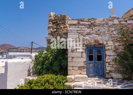 Un vecchio muro di mattoni con una porta blu e una croce in cima Foto Stock