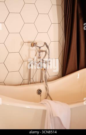 Un bagno elegante ed elegante con splendide piastrelle esagonali e vasca indipendente Foto Stock