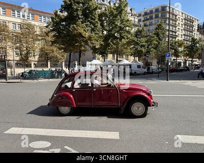 Parigi, Francia. 6 settembre 2025. Una scena di strada a Parigi con una Citroën 2CV rossa d'epoca che attraversa una fila di eleganti edifici Haussmanniani il 6 settembre 2025. Pedoni e altri veicoli condividono l'ampia strada sotto un cielo chiaro e luminoso. (Foto di Samuel Rigelhaupt/Sipa USA) credito: SIPA USA/Alamy Live News Foto Stock