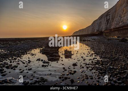 Bassa marea e tramonto sulla costa, a Peacehaven nel Sussex Foto Stock