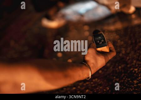 Milano, italia 20 settembre 2025: Mano che regge un termometro a infrarossi, puntandolo verso una pila di chicchi di caffè tostati scuri sotto una luce calda e soffusa, ensur Foto Stock