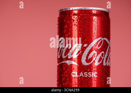Una lattina di Coca-Cola Classic è seduta su uno sfondo rosso. La bomboletta è bagnata e presenta condensa Foto Stock