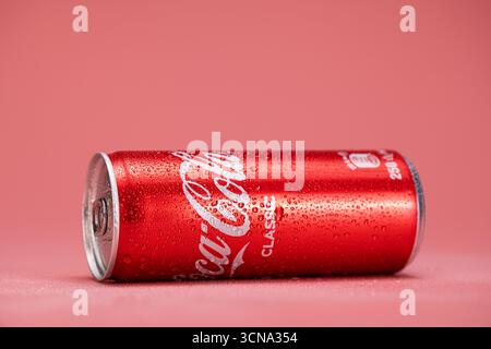 Una lattina di Coca-Cola Classic è seduta su una superficie rosa. La bomboletta è bagnata e presenta condensa Foto Stock